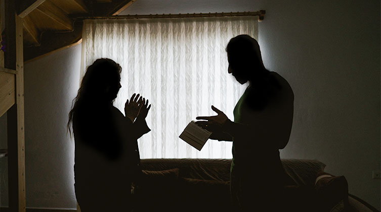 Ein Mann und eine Frau reden in einem dunklen Raum mit einem Buch in der Hand