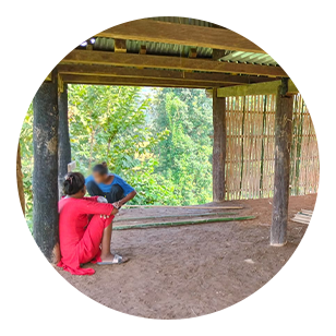 Zwei Erwachsene sitzen in einem offen Haus in den Wäldern Nepals