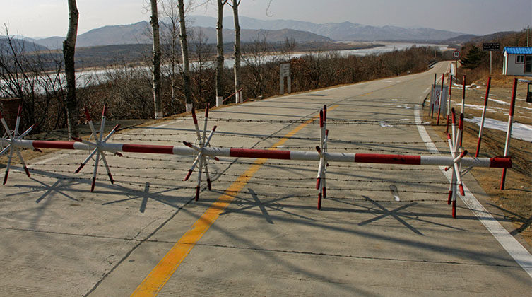 Eine Schranke mit Stacheldraht versperrt eine Bergstraße