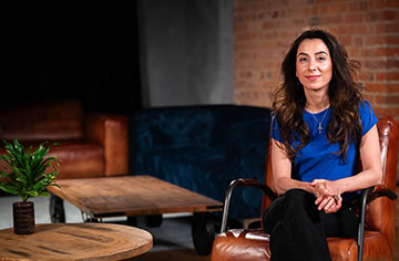 Eine Frau sitzt auf einem Sessel und lächelt in die Kamera