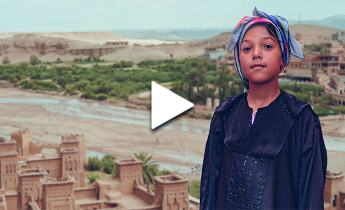 Eine Frau steht in einer Wüste vor einem Dorf