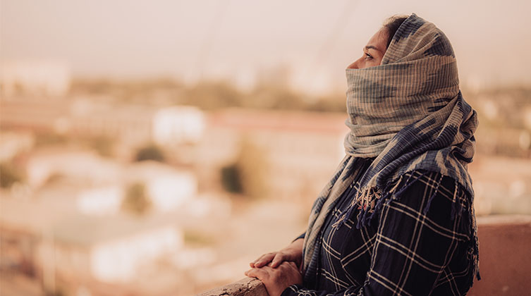 Eine verschleierte Frau blickt auf eine Stadt