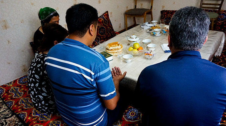 Eine Familie sitzt um einen Esstisch und betet