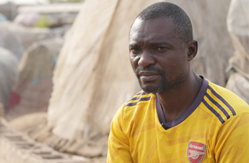 Ein Mann mit gelbem Trikot sitzt vor einigen Zelten