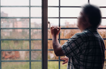 Ein Mann steht vor einem Fenster mit Gittern