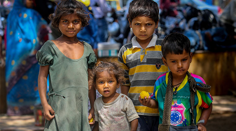 Vier Kinder stehen dicht beieinander und schauen in die Kamera