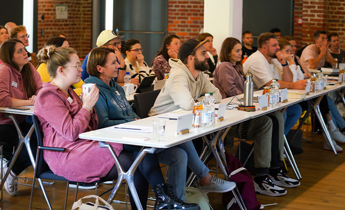 Viele menschen sitzen an Tischen in einem Seminar