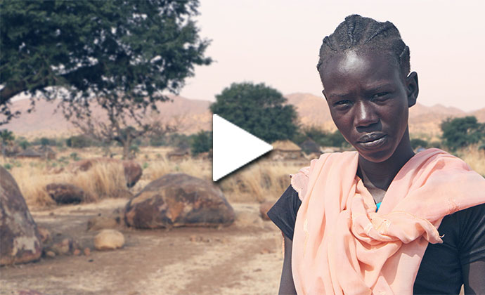 Eine afrikanische Frau in einer Halbwüste blickt in die Kamera 