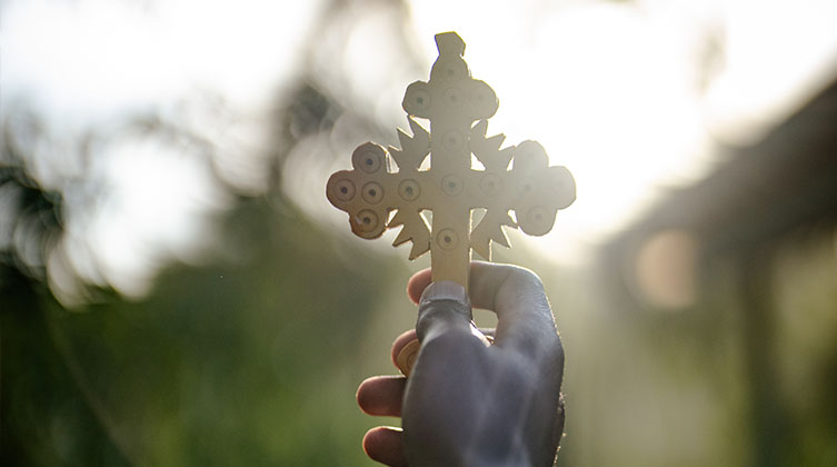 Ein geschnitztes Kreuz wird in die Luft gehalten