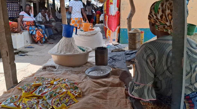 Eine Frau sitzend an ihrem Stand auf dem lokalen Markt.