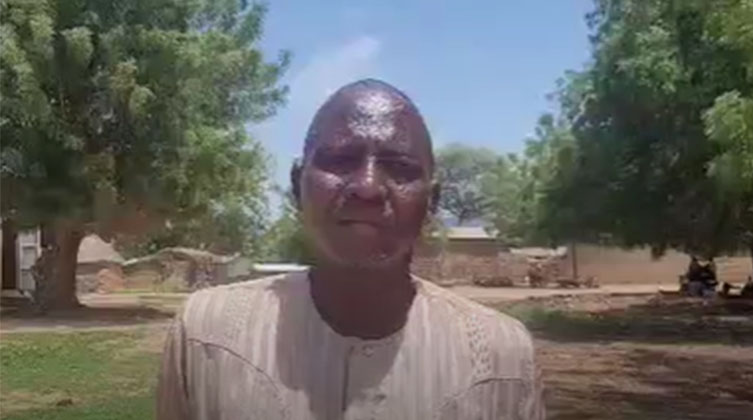 Ein afrikanischer Mann steht vor einem Dorf