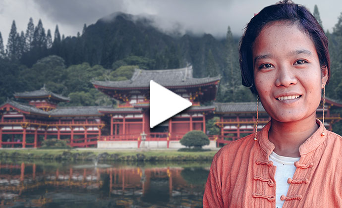 Eine Frau aus dem asiatischem Raums steht vor einem Tempel in den bergigen Wäldern.