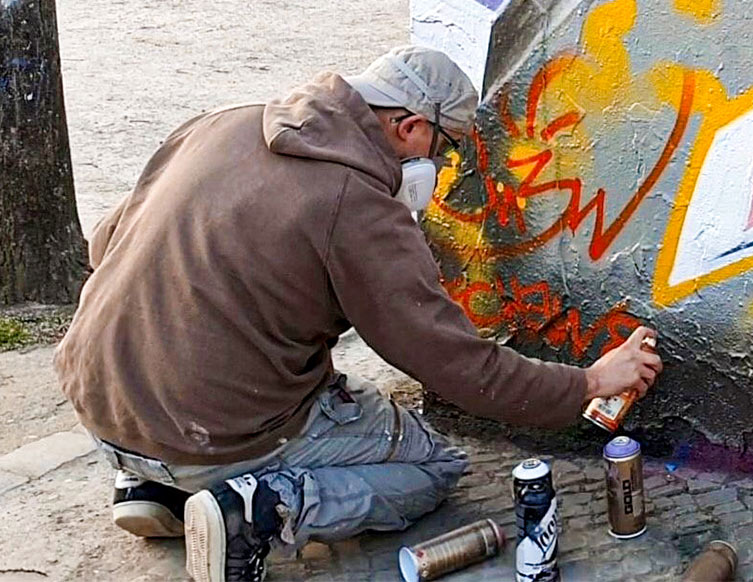 Der Künstler Chew sprüht ein Graffiti an eine offizielle Graffiti-Wand