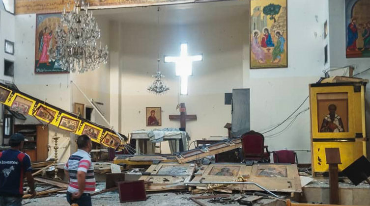 Menschen stehen in einer zerstörten Kirche