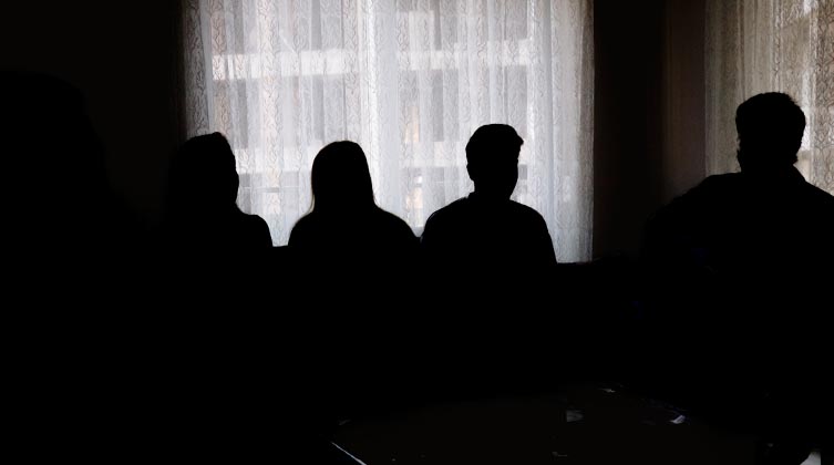 Vier Personen stehen in einem dunklen Raum vor einem Fenster