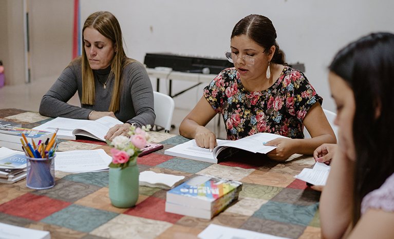 Mehrere Frauen sitzen an einem Tisch und lesen