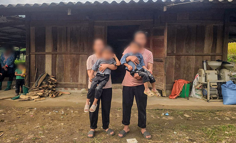 Zwei Erwachsene stehen vor einer Hütte mit zwei Kindern