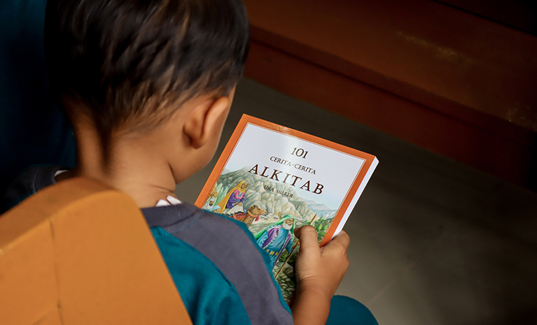 EIn Junge hält eine Kinderbibel in der  Hand