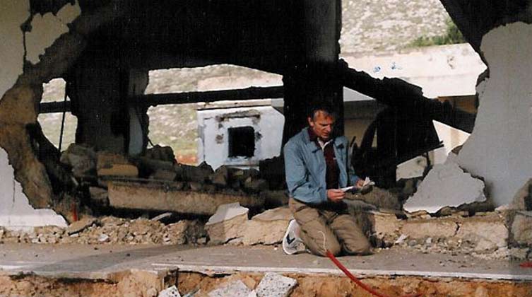 Ein Mann kniet in den Trümmern eines Gebäudes