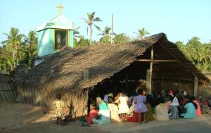 Indien: eine Kirche mit Strohdach im Süden Indiens, darin sitzen Christen zusammen zum Gottesdienst