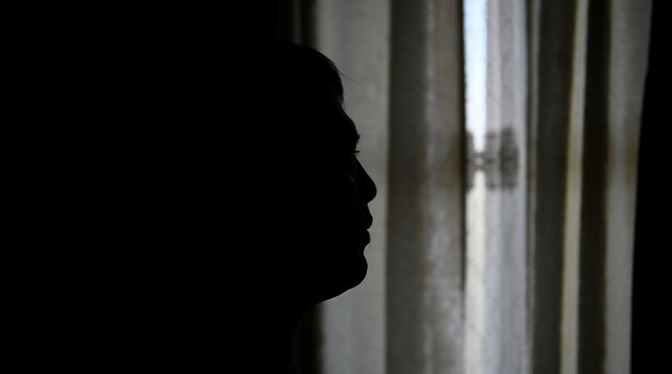 Die dunklen Umrisse einer Person vor einem zugehängten Fenster