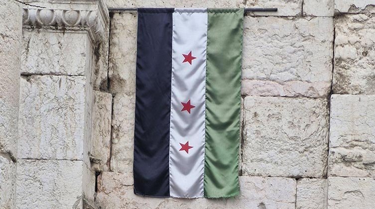 Die syrische Revolutionsflagge an einer Mauer gehisst