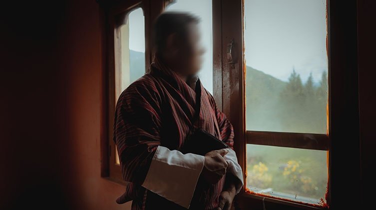 Ein Mann steht in einer Hütte an einem Fenster. Sein Gesicht wurde verfremdet.