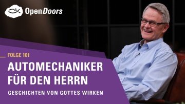 Mann mit Brille und blauem Hemd sitzt auf einem Sofa 