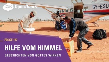 Im Hintergrund wird ein Flugzeug beladen und im Vordergrund ist ein Banner mit der Schrift: "Folge 117 Hilfe vom Himmel Geschichten von Gottes Wirken"