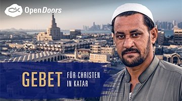 Ein bärtiger Mann mit nach vorne gerichtetem Blick vor einer Stadt 
