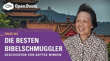 Lachende ältere Dame in leichter Bluse vor asiatischen Häusern
