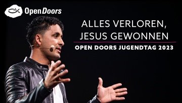 Ein junger Mann mit Lederjacke aus dem Nahen Osten spricht ruhig mit den Händen gestikulierend