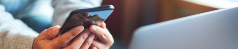 Eine Person hält ihr Smartphone mit beiden Händen.