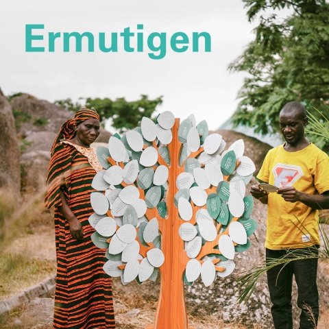 Verfolgte Christen aus Nigeria lesen Ermutigungskarten vom Baum der Ermutigung. Schriftzug „Ermutigen“.