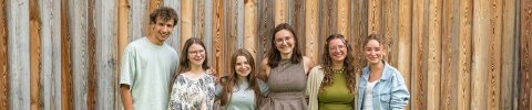 Gruppenbild mit Jugendlichen vor einer Holzwand