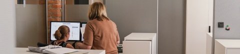 Zwei Frauen vor einem Schreibtisch schauen auf einen Bildschirm