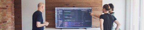 Drei Männer schauen sich auf einem Touchscreen Code an