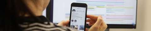 Frau hält ein Smartphone in der Hand und arbeitet