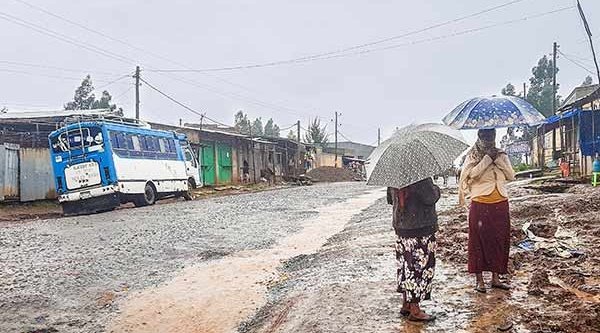 Zwei Frauen stehen im Regen an der matschigen Straße