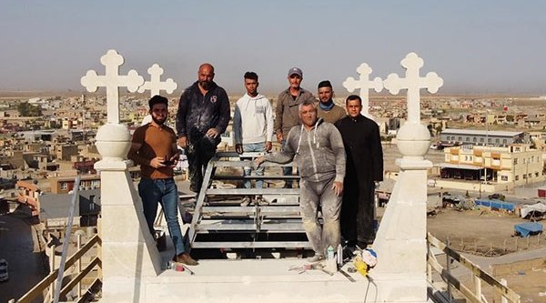 Pfarrer Ammar und Mitarbeiter auf dem Turm der kürzlich renovierten al-Tahira-Kirche in Karakosch. Kirche und Turm waren vom IS zerstört worden.