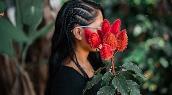 Mädchen hält eine rote Blume vor ihrem Gesicht