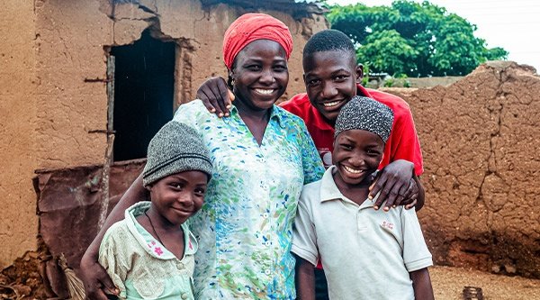 Nigerianische Frau mit ihren Kindern vor ihrem Haus