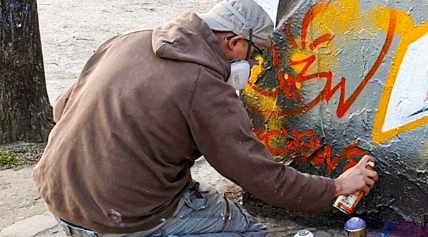 Der Künstler Chew sprüht ein Graffiti an eine offizielle Graffiti-Wand