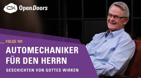 Mann mit Brille und blauem Hemd sitzt auf einem Sofa 