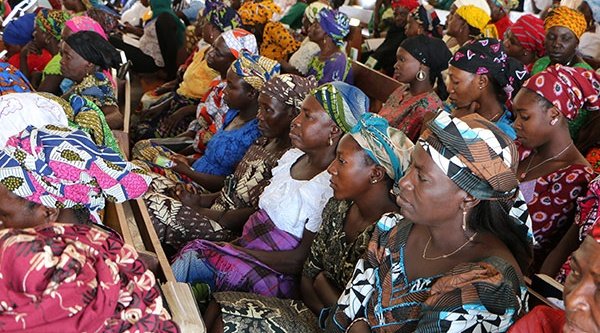 Afrikanische Frauen mit bunter Kleidung sitzen nebeneinander 