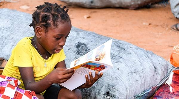 Ein Mädchen aus Mosambik liest in einer Kinderbibel