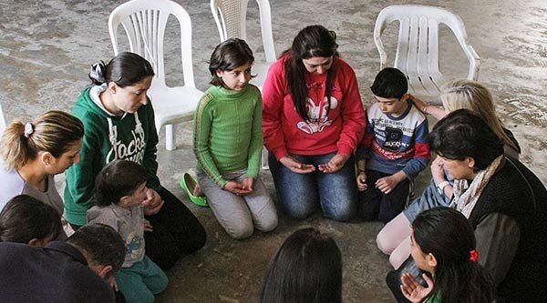 Syrische Christen sitzen kniend im Kreis und beten