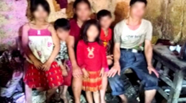 Familie sitzt in farbenfroher Kleidung in einem Zimmer