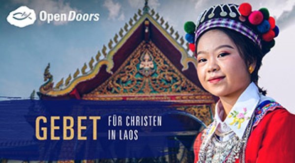 Frau aus Laos steht in traditioneller Kleidung vor einem Gebäude