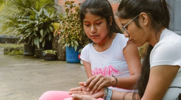 Zwei kolumbianische Mädchen sitzen nachdenklich beieinander